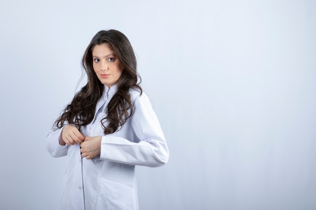 Ujęcie młodego lekarza w białym fartuchu stojącego na szaro.