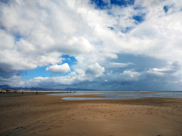 Ujęcie piaszczystej plaży z kilkoma ludzkimi sylwetkami na Fuerteventurze w Hiszpanii.