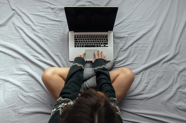 Ujęcie Pod Dużym Kątem Kobiety Piszącej Na Laptopie Siedzącej Na łóżku Ze Skrzyżowanymi Nogami