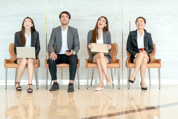Ujęcie portretu zróżnicowanej grupy azjatyckich biznesmenów, którzy patrzą z boku, czekając w kolejce na rozmowę kwalifikacyjną