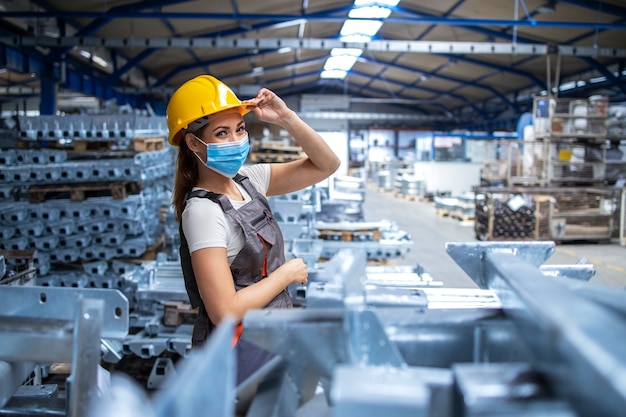 Bezpłatne zdjęcie ujęcie pracownika fabryki kobieta w mundurze i kasku na sobie maskę w zakładzie produkcji przemysłowej