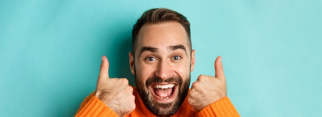 Bezpłatne zdjęcie ujęcie w głowę podekscytowanego brodatego mężczyzny pokazującego kciuk do góry, chwalącego coś dobrego, aprobującego i lubiącego produkt ul