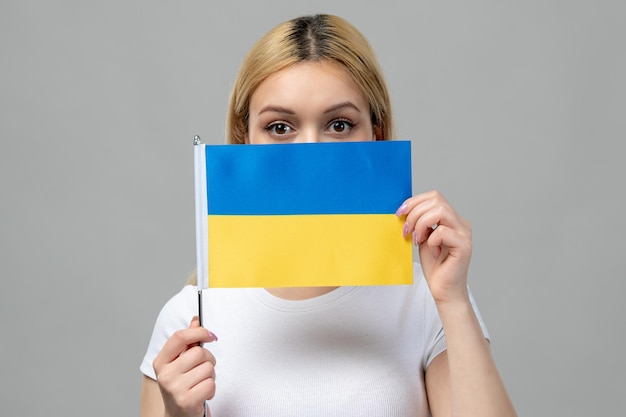 Bezpłatne zdjęcie ukraina rosyjski konflikt blondynka urocza dziewczyna z czerwoną szminką i ukraińską flagą zakrywającą twarz