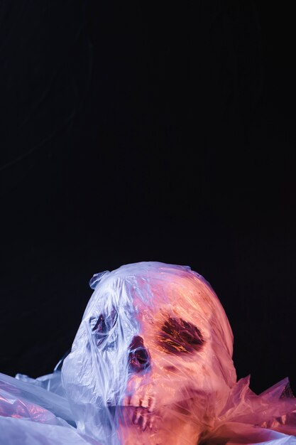 Upiorna czaszka w plastikowym materiale oświetlona fioletowym światłem