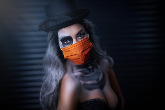 Upiorna kobieta w halloweenowym gotyckim makijażu nosząca maskę na twarz z powodu ograniczeń covid-19