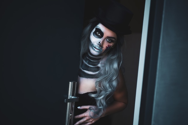 Upiorny portret kobiety w halloween gotyckiego makijażu otwierających drzwi