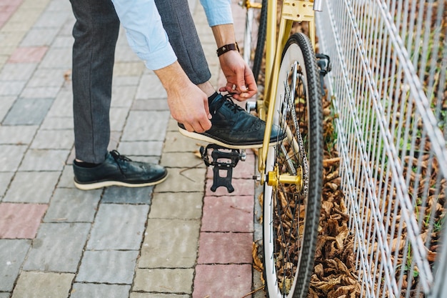 Bezpłatne zdjęcie upraw mężczyzna wiąże koronki blisko bicyklu