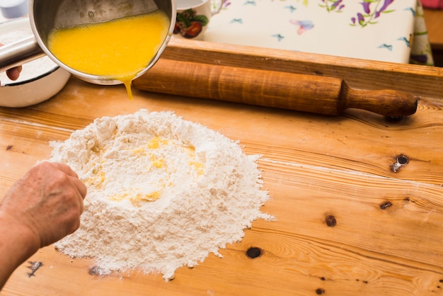 Bezpłatne zdjęcie uprawa osobę wlewając jajka na mąkę