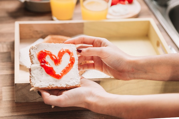 Bezpłatne zdjęcie uprawy kobieta trzyma toast z dżemem serca