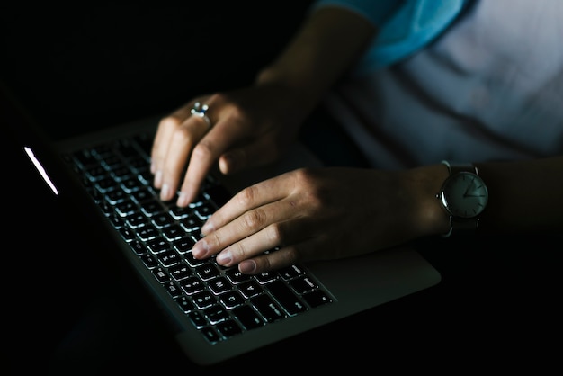Uprawy kobieta używa laptop w ciemnym pokoju