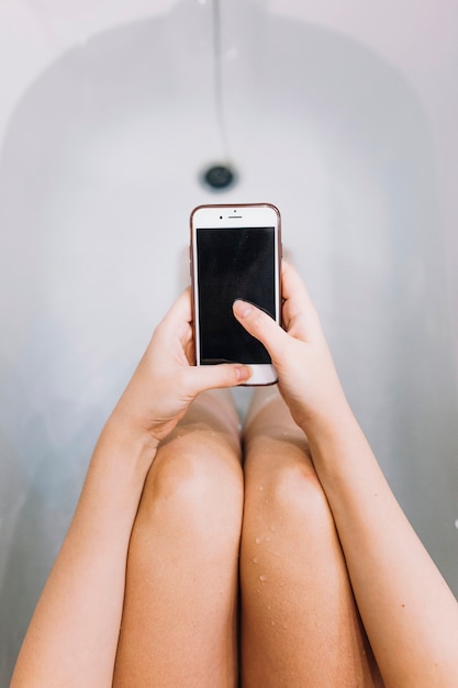 Uprawy kobieta używa smartphone w wannie