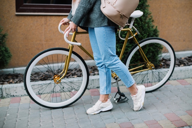 Bezpłatne zdjęcie uprawy kobiety odprowadzenie z bicyklem