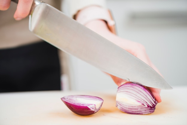Bezpłatne zdjęcie uprawy rąk do krojenia cebuli z nożem