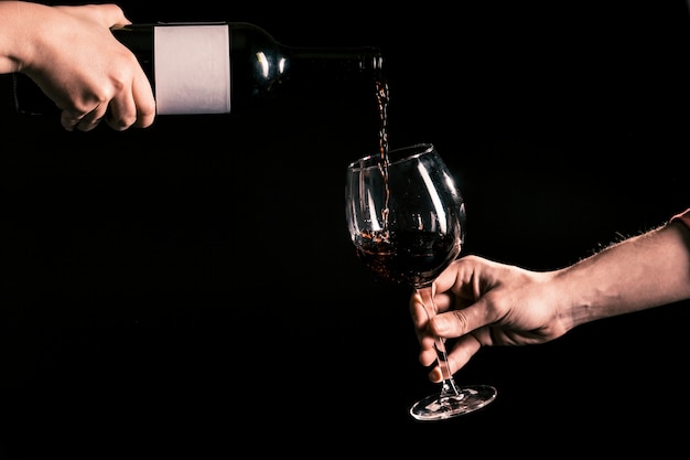 Uprawy rąk wlewając wino do szklanki