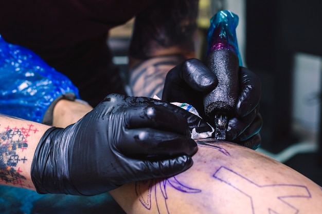 Uprawy ręce robi tatuaż z maszyną
