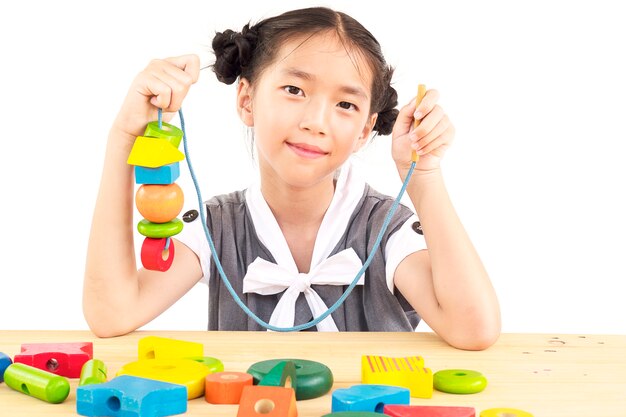 Urocza azjatykcia dziewczyna bawić się kolorową drewnianą blokową zabawkę
