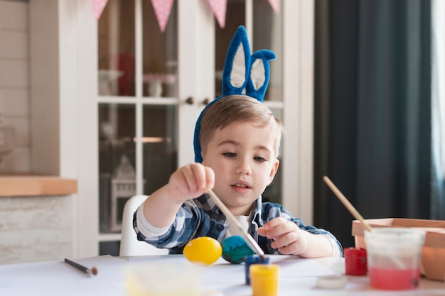 Bezpłatne zdjęcie urocza chłopiec maluje jajka na easter