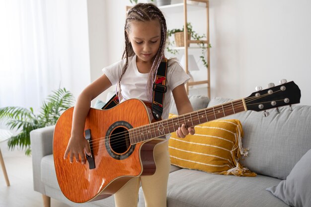 Urocza dziewczyna grająca na gitarze w domu