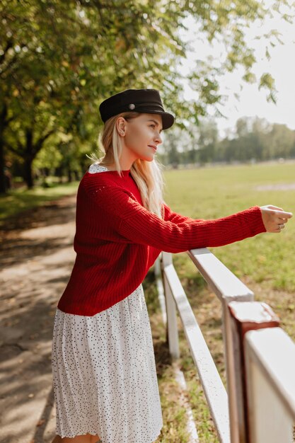 Urocza dziewczyna z naturalnym makijażem pozuje czule Piękna kobieta w ładnej białej sukni relaksuje na świeżym powietrzu