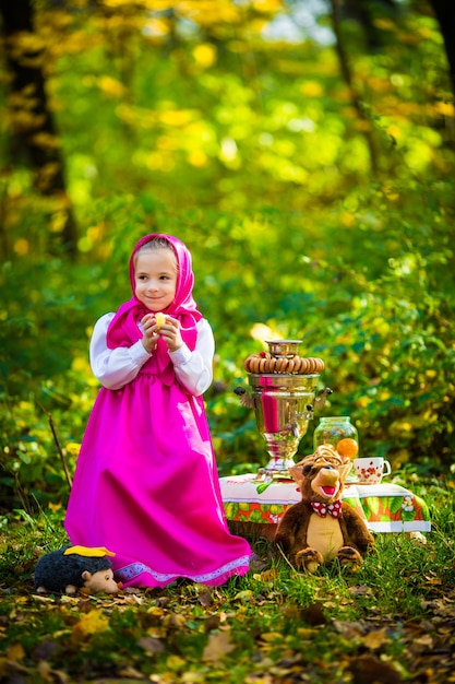 Urocza dziewczynka w różowym szaliku i sukience, białej kurtce jak Masza i niedźwiedź z kreskówki.