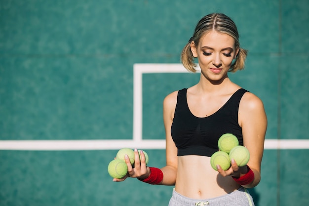 Bezpłatne zdjęcie urocza kobieta trzyma piłki tenisowe