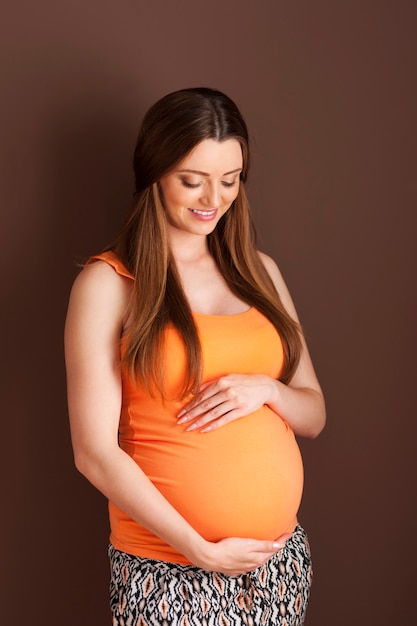 Urocza kobieta w ciąży obejmując brzuch