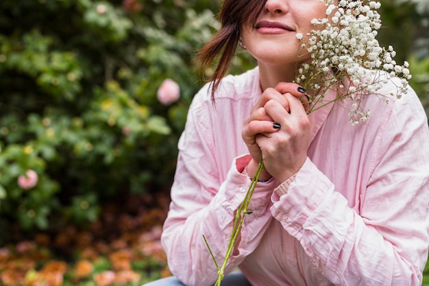 Bezpłatne zdjęcie urocza kobieta z bukietem roślin z białymi kwiatami w pobliżu twarzy