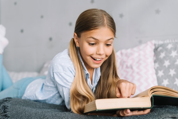 Bezpłatne zdjęcie urocza mała dziewczynka czyta książkę