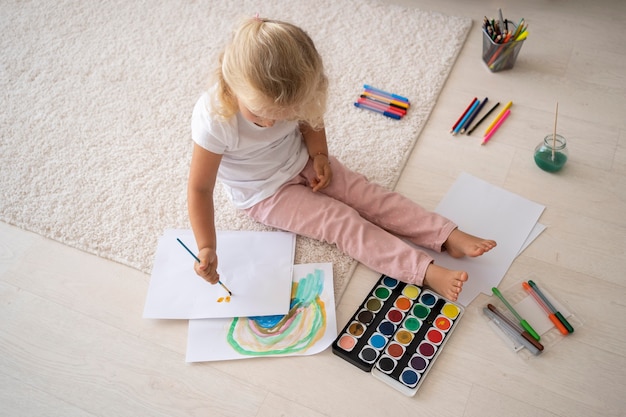 Urocza mała dziewczynka maluje na papierze w domu