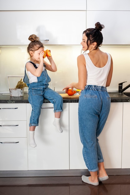 Urocza młoda dziewczyna bawić się z matką w kuchni