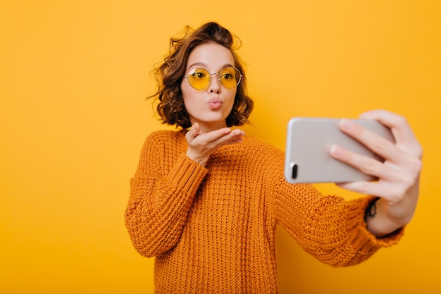 Urocza modelka wysyłająca pocałunek podczas robienia selfie