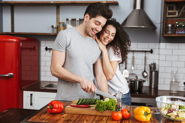 Urocza para mężczyzna i kobieta wspólnie gotują sałatkę z warzywami w nowoczesnej kuchni w domu