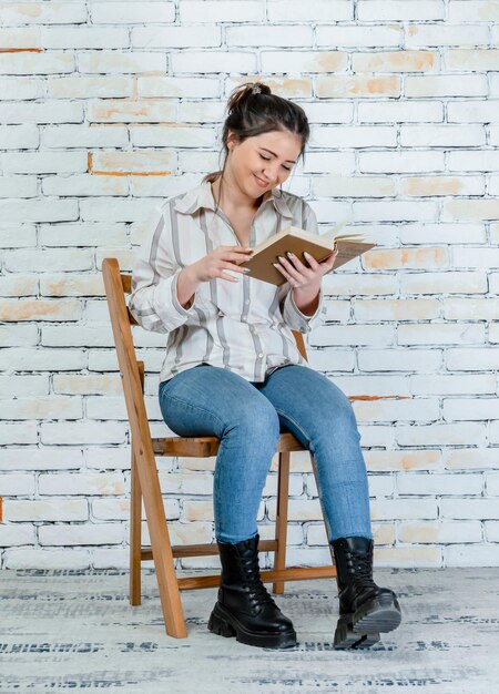 Urocza uśmiechnięta dziewczyna czytająca książkę Wysokiej jakości zdjęcie