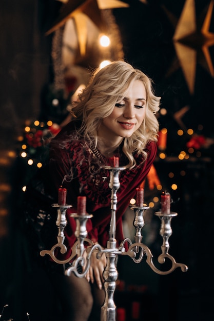 Urocze kobiety blondynka patrzy na świece stojące w pokoju z pięknym wystrojem Bożego Narodzenia