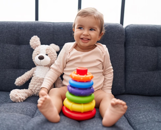 Bezpłatne zdjęcie urocze latynoskie dziecko bawiące się grą w obręcze siedzące na kanapie w domu
