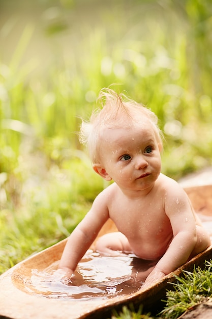 Uroczy mały chłopiec bierze kąpiel na trawniku w zielonym letnim parku