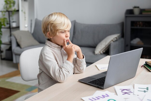 Uroczy mały chłopiec robi sesję logopedyczną online