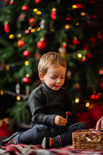 Uroczy młody chłopak bawi się zabawkami świątecznymi
