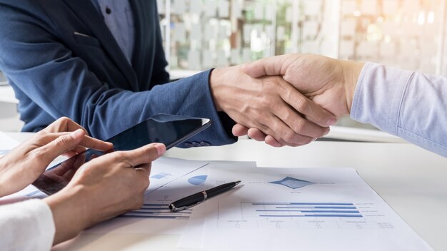 Uścisk dłoni dwóch mężczyzn wykazujących zgodę na podpisanie umowy lub umowy między ich firmami, firmami, przedsiębiorstwami
