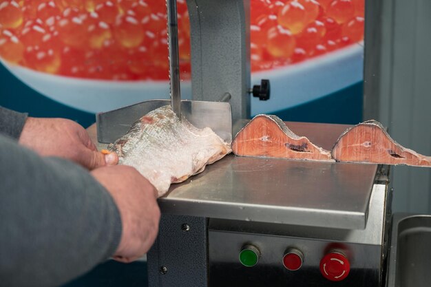 Usługa krojenia mrożonej ryby łososiowej na steku w supermarkecie rybnym przy użyciu profesjonalnego sprzętu
