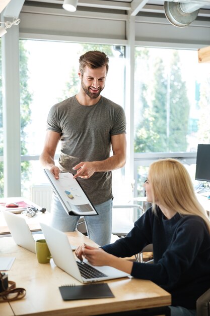 Uśmiechnięci młodzi koledzy siedzi w biurowym coworking