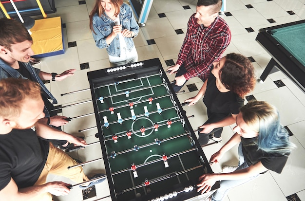 Uśmiechnięci młodzi ludzie bawić się stołowego futbol podczas gdy indoors