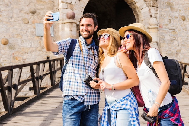 Bezpłatne zdjęcie uśmiechnięci młodzi przyjaciele bierze selfie na telefonie komórkowym