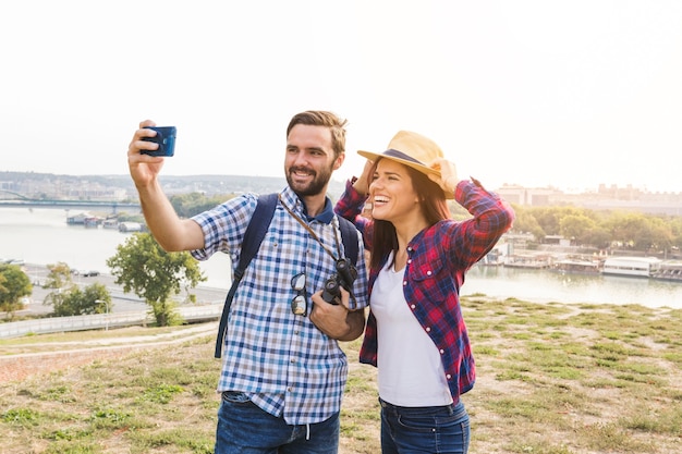 Uśmiechnięci potomstwa dobierają się brać selfie na telefonie komórkowym przy outdoors