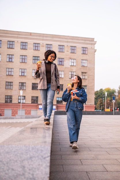 Uśmiechnięci przyjaciele z książkami i kawą na świeżym powietrzu