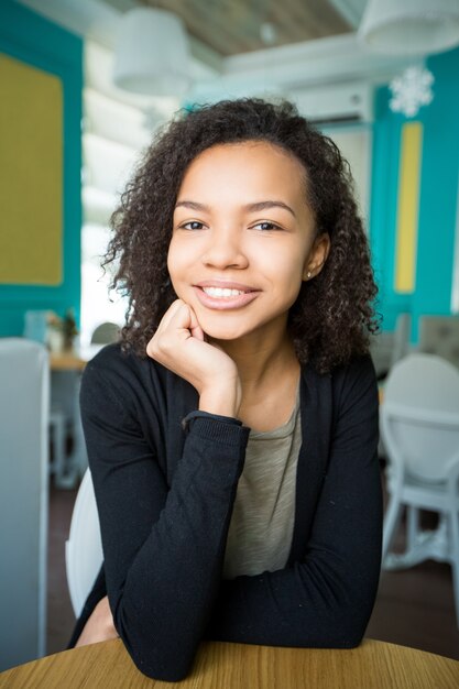 Uśmiechnięta African American girl siedzi w kawiarni