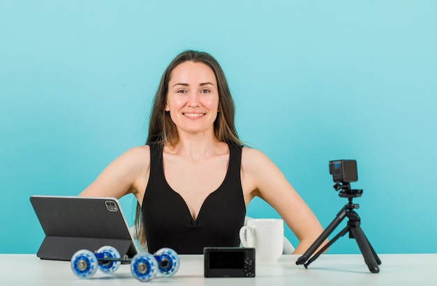 Uśmiechnięta blogerka patrzy na kamerę na niebieskim tle