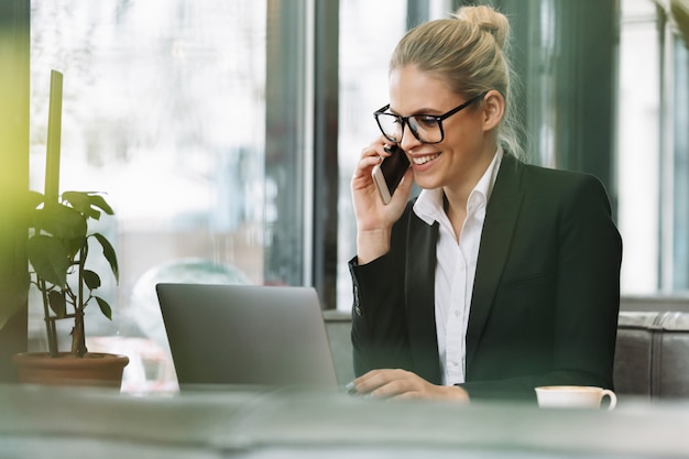 Uśmiechnięta blondynka biznes kobieta rozmawia przez telefon komórkowy