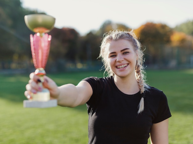 Bezpłatne zdjęcie uśmiechnięta blondynki kobieta trzyma trofeum