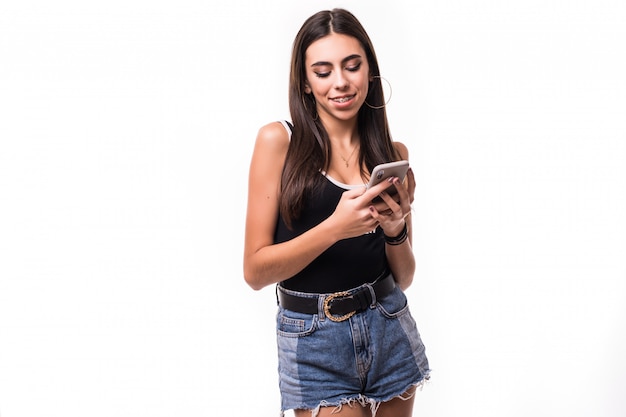 Uśmiechnięta brunetka przewija ogólnospołecznych środki na jej telefonie odizolowywającym